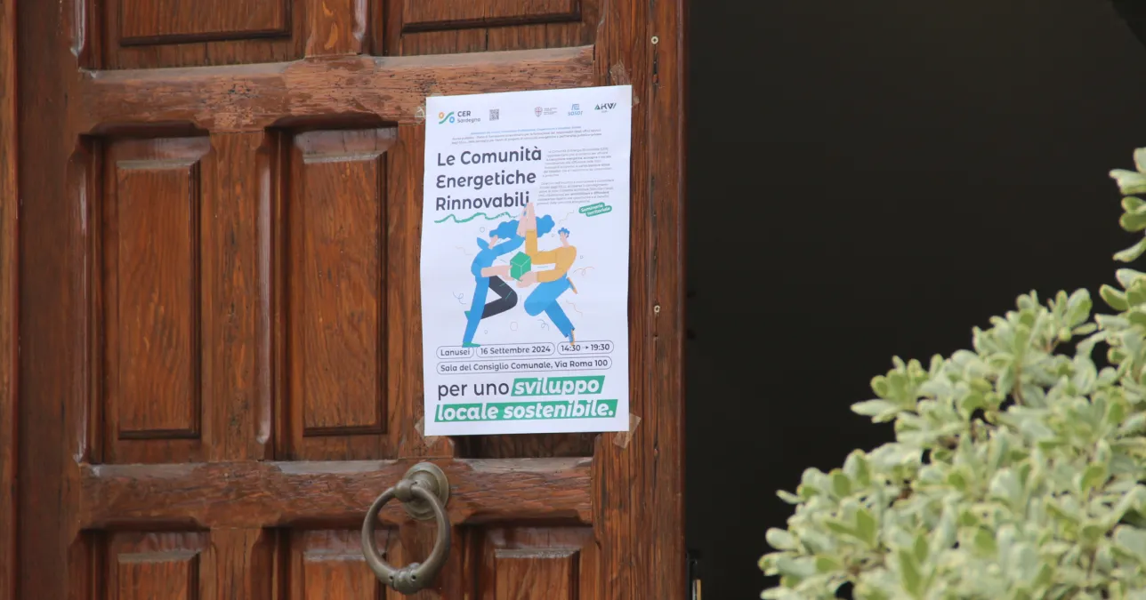 Dettaglio del portone d'ingresso del comune di Lanusei, su cui è affissa locandina a colori per il seminario informativo "Le comunità energetiche rinnovabili per uno sviluppo locale sostenibile".