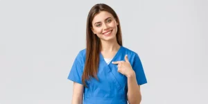 Corso OSS (Operatore Socio Sanitario) Cagliari. Ragazza sorridente con camice azzurro e capelli lisci castani sino alle scapole.