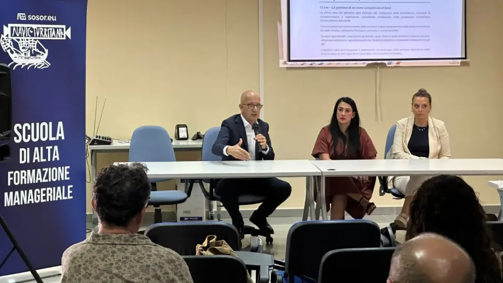 Pubblico in una sala conferenze assiste a inaugurazione Scuola Alta Formazione CIPSS. Un cartello sulla sinistra riporta la scritta "Sosor CIPSS, Scuola di alta formazione manageriale". Al tavolo dei relatori, Franco Sabatini parla al microfono. Accanto a lui presidente del CIPSS Simona Fois e Dalila Masia, docente del corso Negoziazione efficace