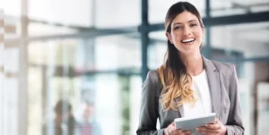 Giovane donna in tailleur sorridente tiene in mano un tablet