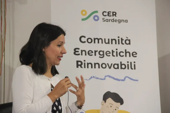 Enrica Puggioni al microfono durante incontro CER Sardegna. Ha capelli castani alle spalle e un maglione bianco
