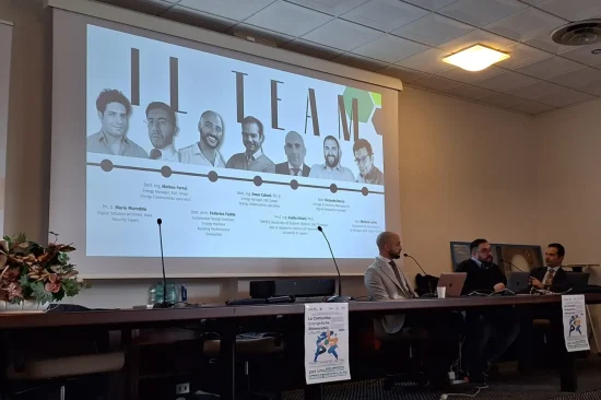 Villacidro, 2 dicembre 2024 -Un momento del 6 seminario CER Sardegna. Tre relatori sono seduti a un lungo tavolo, alle loro spalle è proiettata una foto del gruppo di lavoro, composto da 7 uomini.